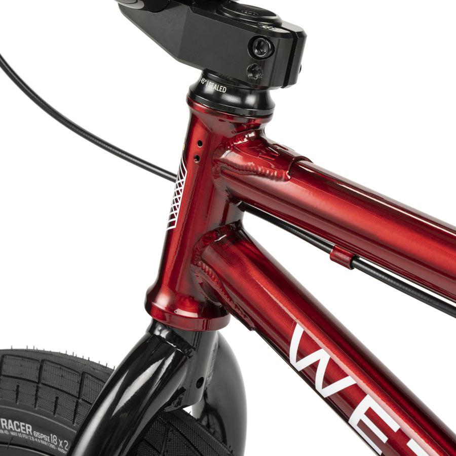 Close-up of the front frame, fork, and tire of a red Wethepeople CRS 18 Inch Bike with white lettering and a visible brake cable.