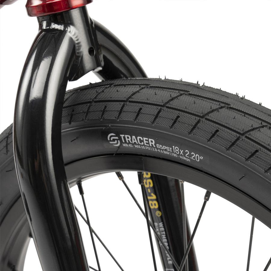 Close-up of a black front tire with "Tracer 18 x 2.20" label on a black rim, showing part of the fork—perfect detail on the Wethepeople CRS 18 Inch Bike, an awesome BMX for kids.