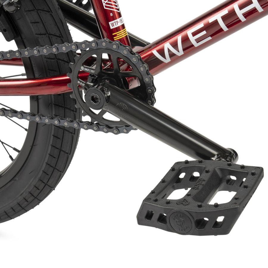 Close-up of the Wethepeople CRS 18 Inch Bike’s crankset, chainring, chain, and black flat pedal on its vivid red frame—a BMX bike perfectly sized for young riders looking for their first kids’ BMX.