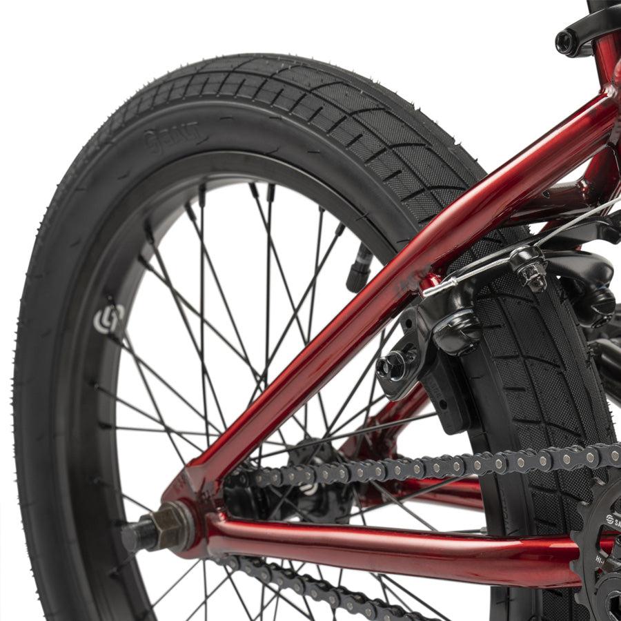 Close-up of the rear wheel, tire, and chain of the Wethepeople CRS 18 Inch Bike, highlighting its red frame and brake mechanism.