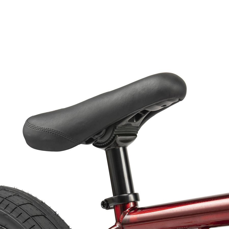 Close-up of a black seat on the Wethepeople CRS 18 Inch Bike in red, showing part of the rear tire on this kids BMX.