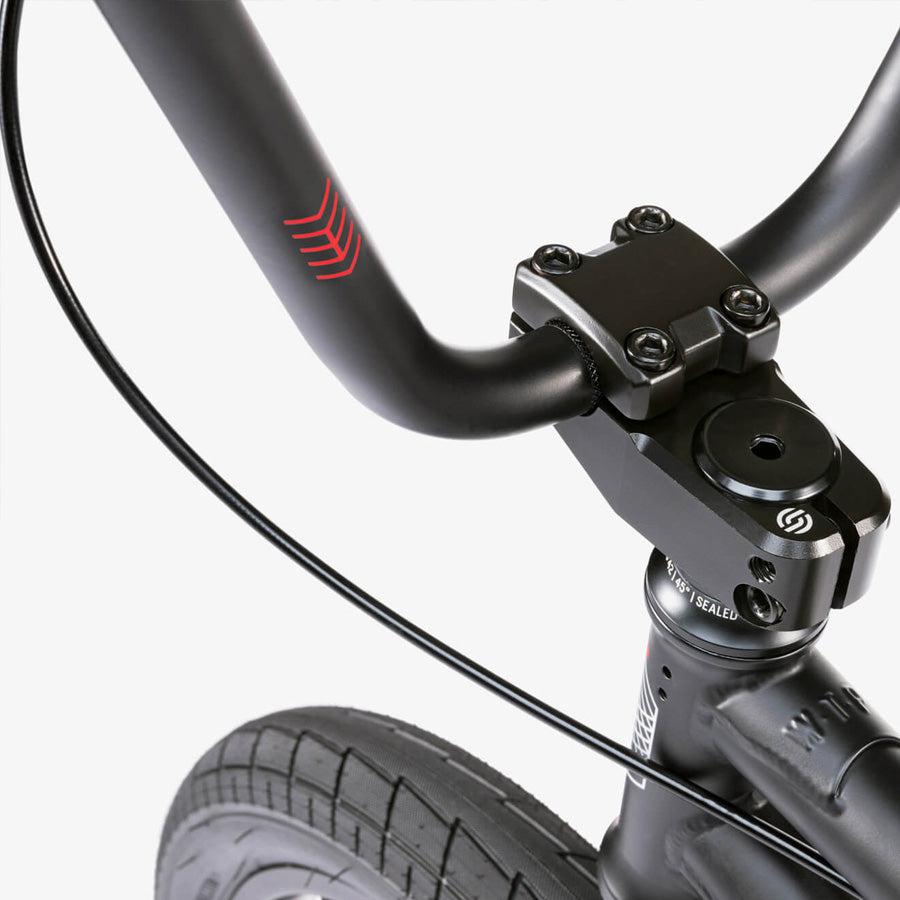 Close-up of the Wethepeople CRS 18 Inch Bike’s black handlebar, stem, and front tire against a plain light background—ideal for anyone looking for an 18 inch BMX.