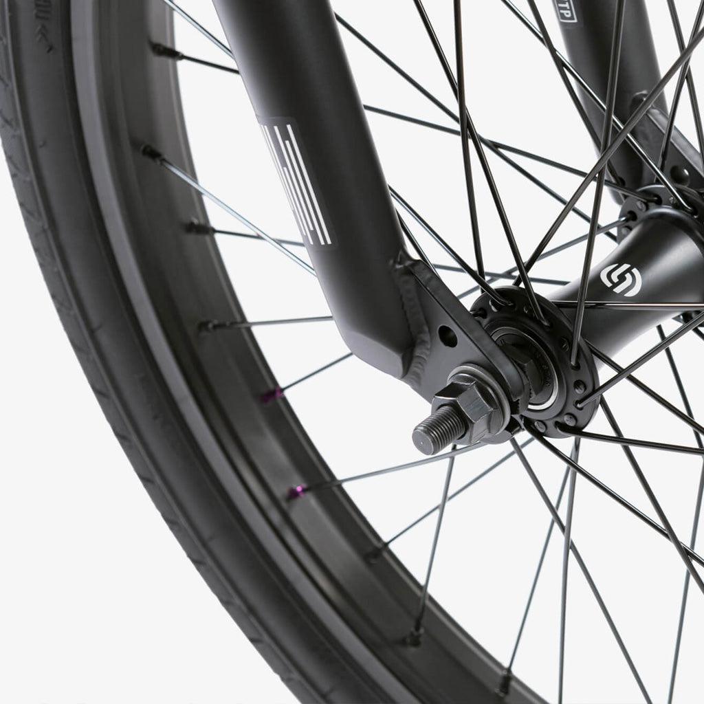 A close up view of a black bicycle wheel featuring the Wethepeople CRS 20 Inch Bike and the Salt Rookie Chromoly Three Piece Cranks.