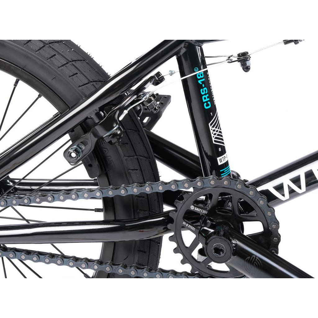 Close-up of the Wethepeople CRS FS 18 Inch Bike’s rear wheel, highlighting its chain, gear, brake, frame, and the "CRS-18" sticker.