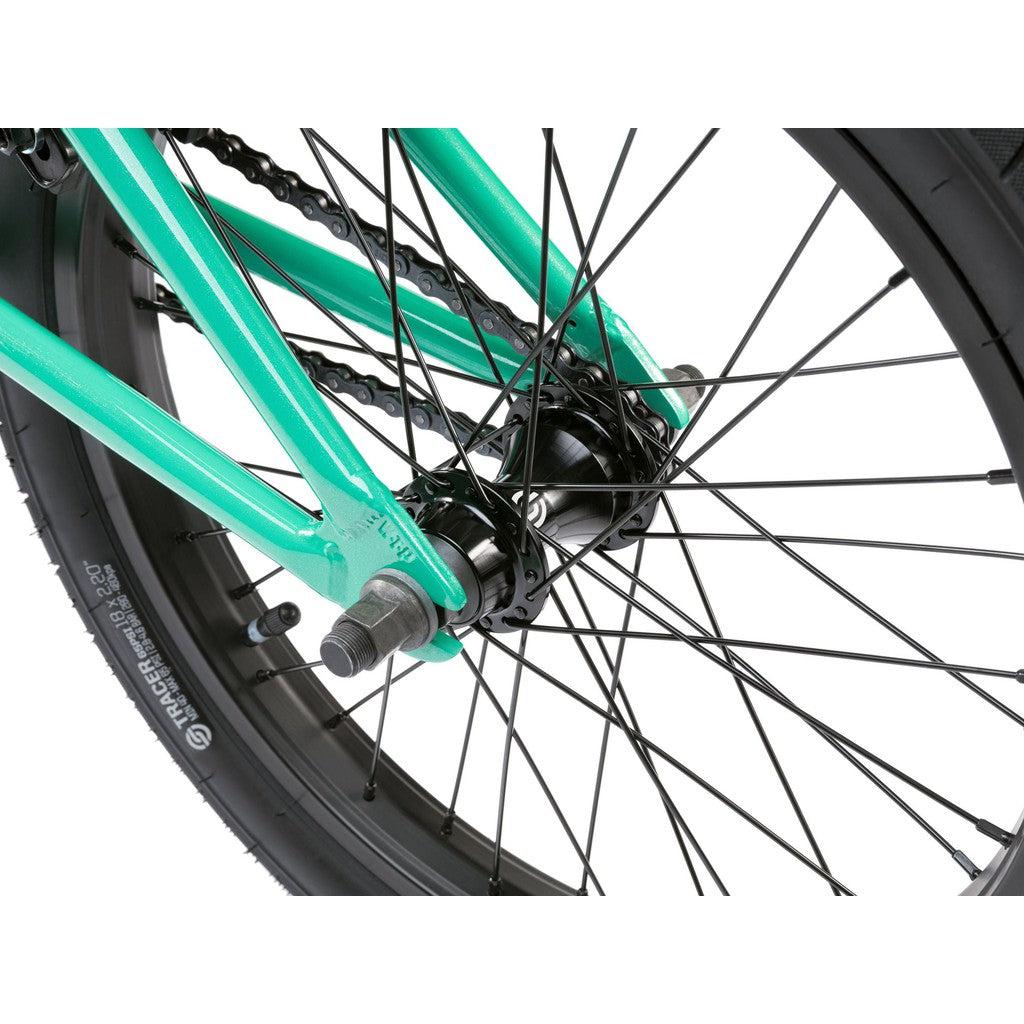 Close-up view of the Wethepeople CRS FS 18 Inch Bike's rear wheel hub, highlighting the spokes, chain, axle, gyro system, and mint green frame.