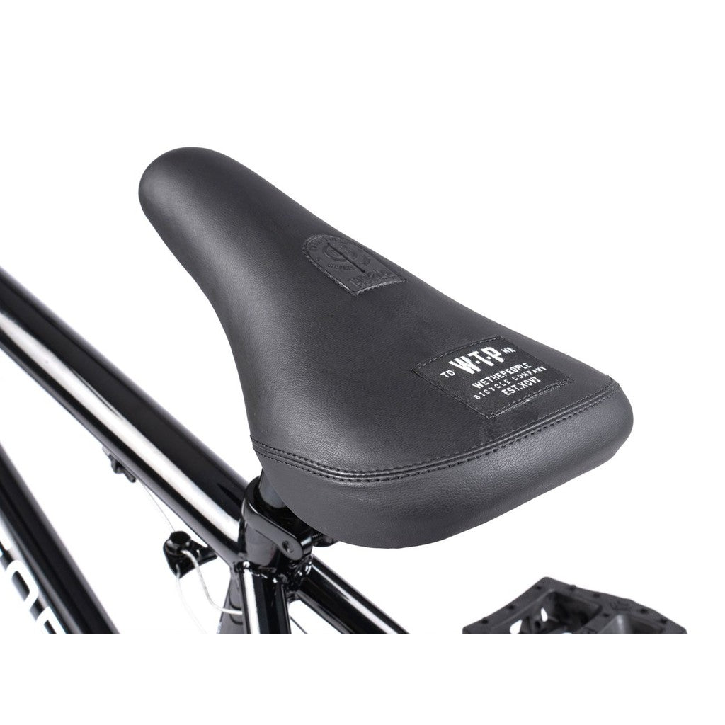 Close-up of the black seat attached to the Wethepeople CRS FS 18 Inch BMX freestyle bike, showing its gyro system, label, and a partial view of the pedal and rear wheel.