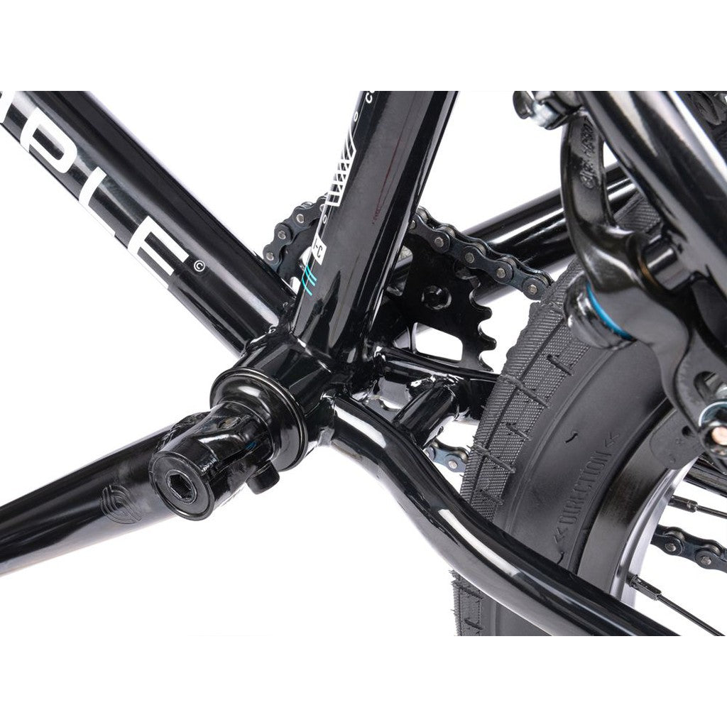 Close-up view of the Wethepeople CRS FS 18 Inch Bike's bottom bracket, displaying the crank spindle, chainring, rear tire, and black gyro-equipped frame components.