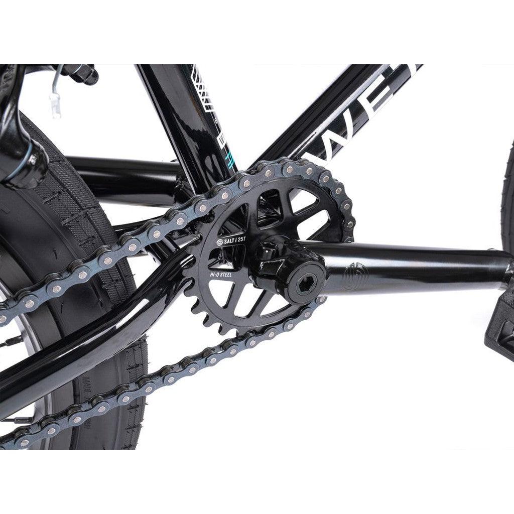 Close-up of the Wethepeople CRS FS 18 Inch Bike's drivetrain, highlighting the chain, chainring, crank arm, and part of the rear tire on this gyro-equipped BMX freestyle ride.