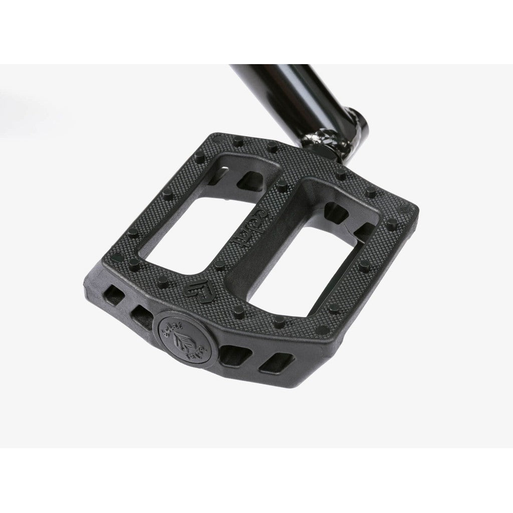 Close-up of a black BMX pedal with textured surface and raised grip studs, attached to the crank arm of the Wethepeople CRS FS 18 Inch Bike, shown against a white background.