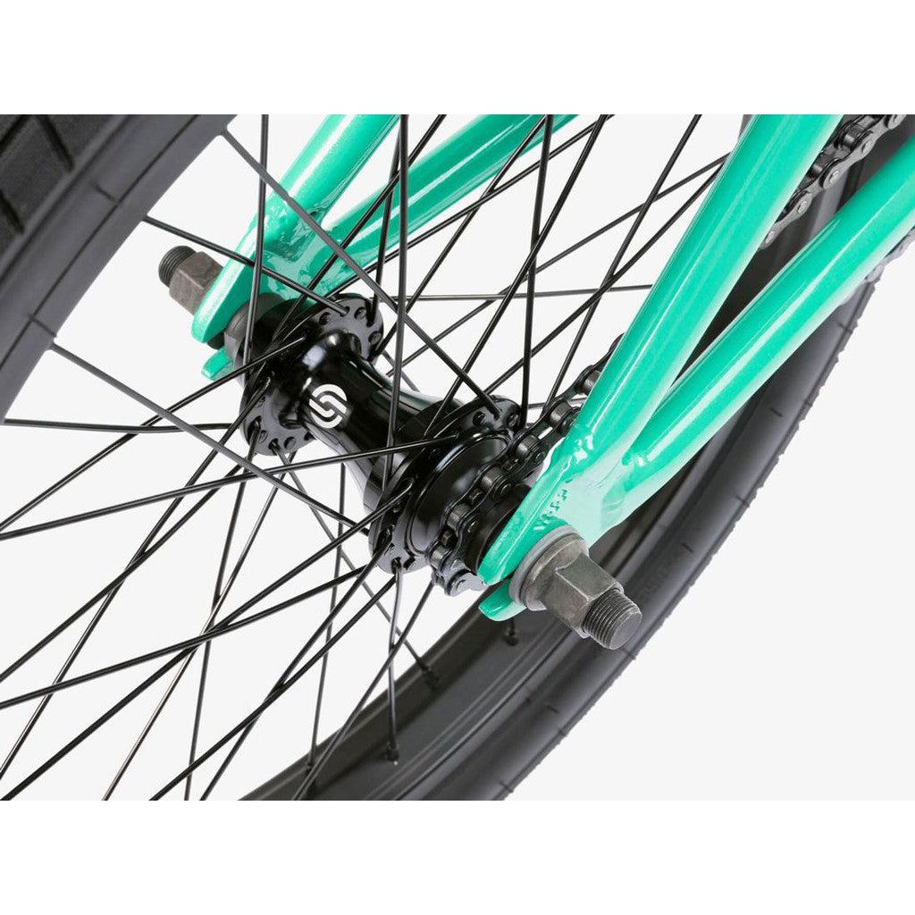 Close-up view of the Wethepeople CRS FS 18 Inch Bike’s rear wheel hub with black spokes, silver nuts, and a green frame. The 18-inch, gyro-equipped setup delivers smooth performance and precise control for BMX tricks.