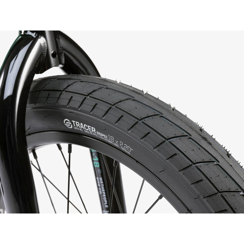 Close-up of a black "Tracer 18 x 2.20" tire mounted on the Wethepeople CRS FS 18 Inch Bike, with the front fork in view.
