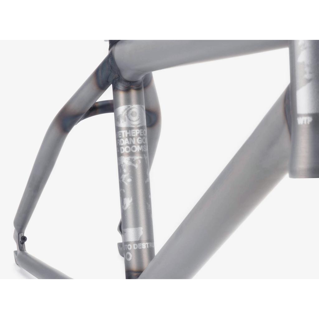 Close-up of the Wethepeople Doomsayer Frame in matte metal, showcasing the top tube, seat tube, part of the down tube with visible welds, progressive geometry lines, and a partially shown logo and text.