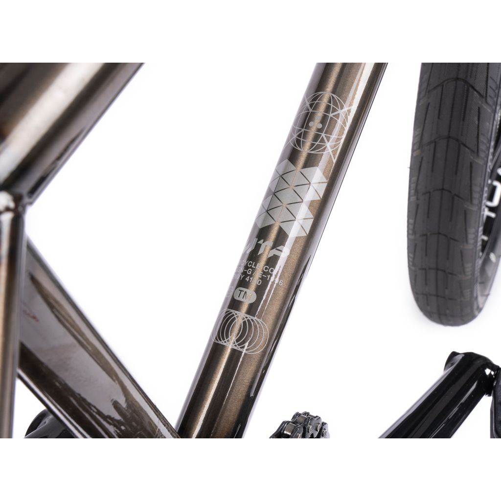 Close-up of a Wethepeople Envy 20 Inch Bike frame featuring geometric designs, alongside a black tire. The metallic finish catches the light and highlights the texture—a stunning BMX masterpiece.