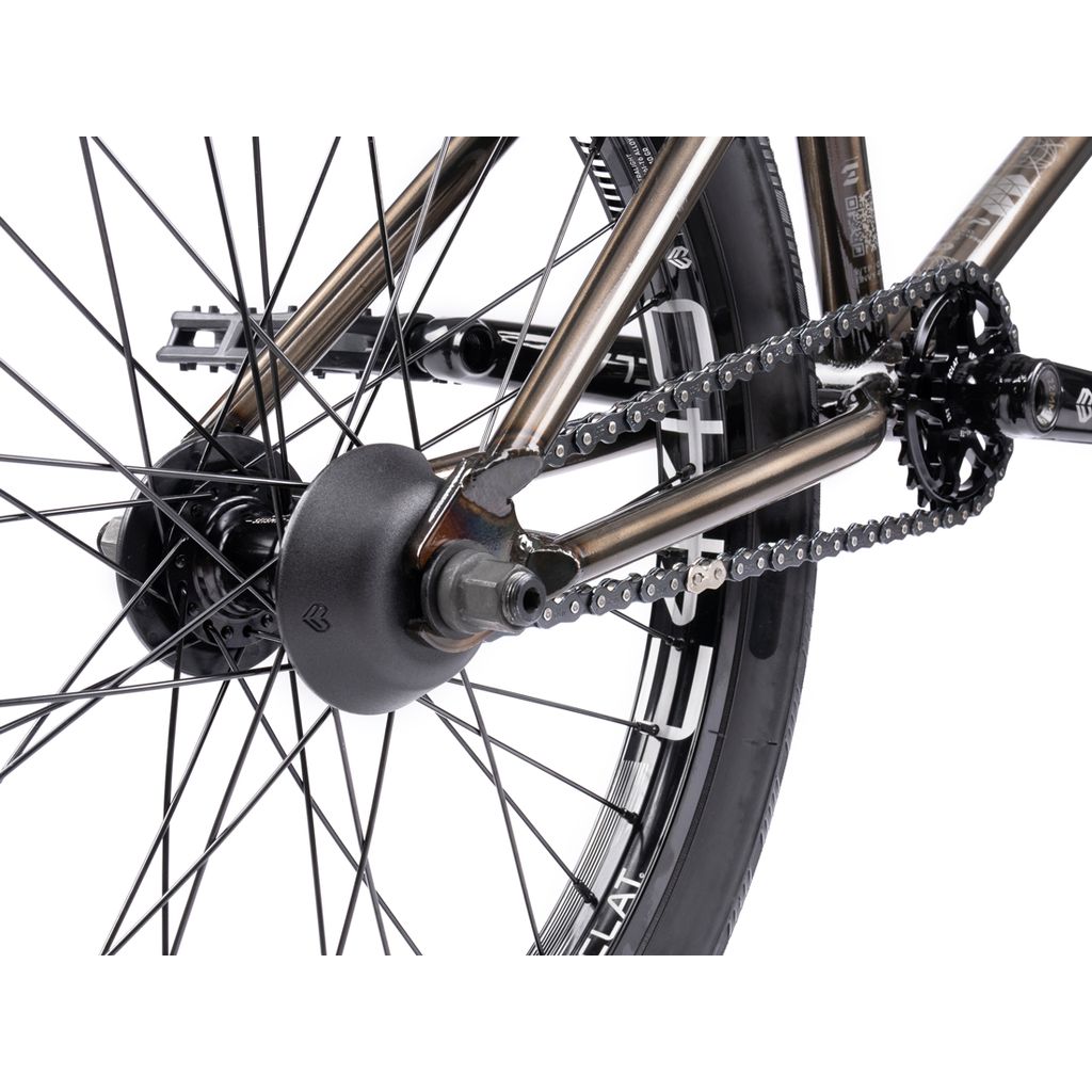 The Wethepeople Envy 20 Inch Bike's rear wheel features Eclat Tibia Cranks, highlighting the chain, spokes, and hub. The metallic frame shines while the black tire with visible treads draws attention.