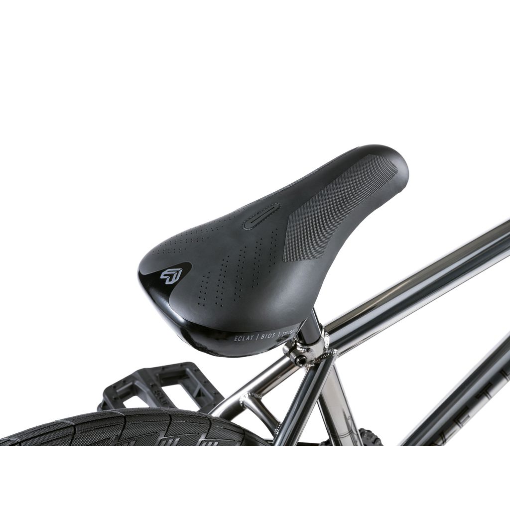Close-up of a bicycle seat on the sleek Wethepeople Envy 20 Inch Bike, complete with a metallic frame and textured tires, showcasing true BMX craftsmanship.
