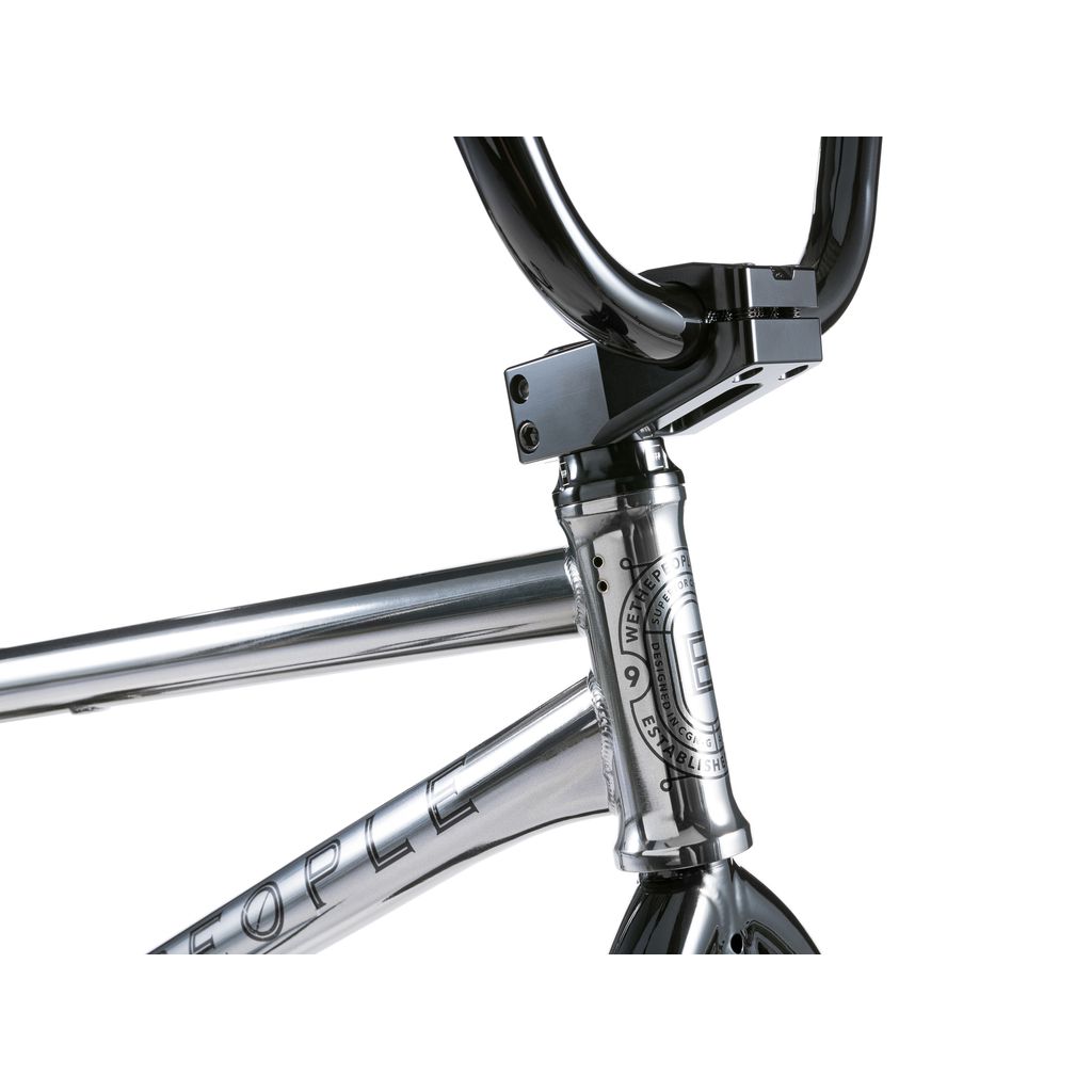 Close-up of a silver Wethepeople Envy 20 Inch Bike frame and black handlebars, featuring a logo and text. The handlebar clamp is secured with visible bolts, highlighting the BMX craftsmanship.