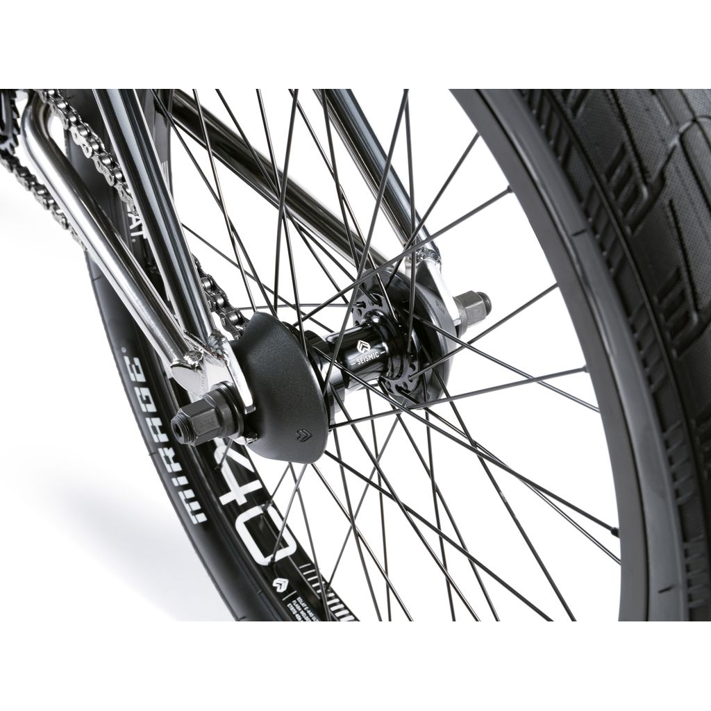 A close-up of the bicycle's rear wheel showcases black spokes, a Mirage tire, and a gear hub with a chain, reflecting craftsmanship akin to the Wethepeople Envy 20 Inch Bike.