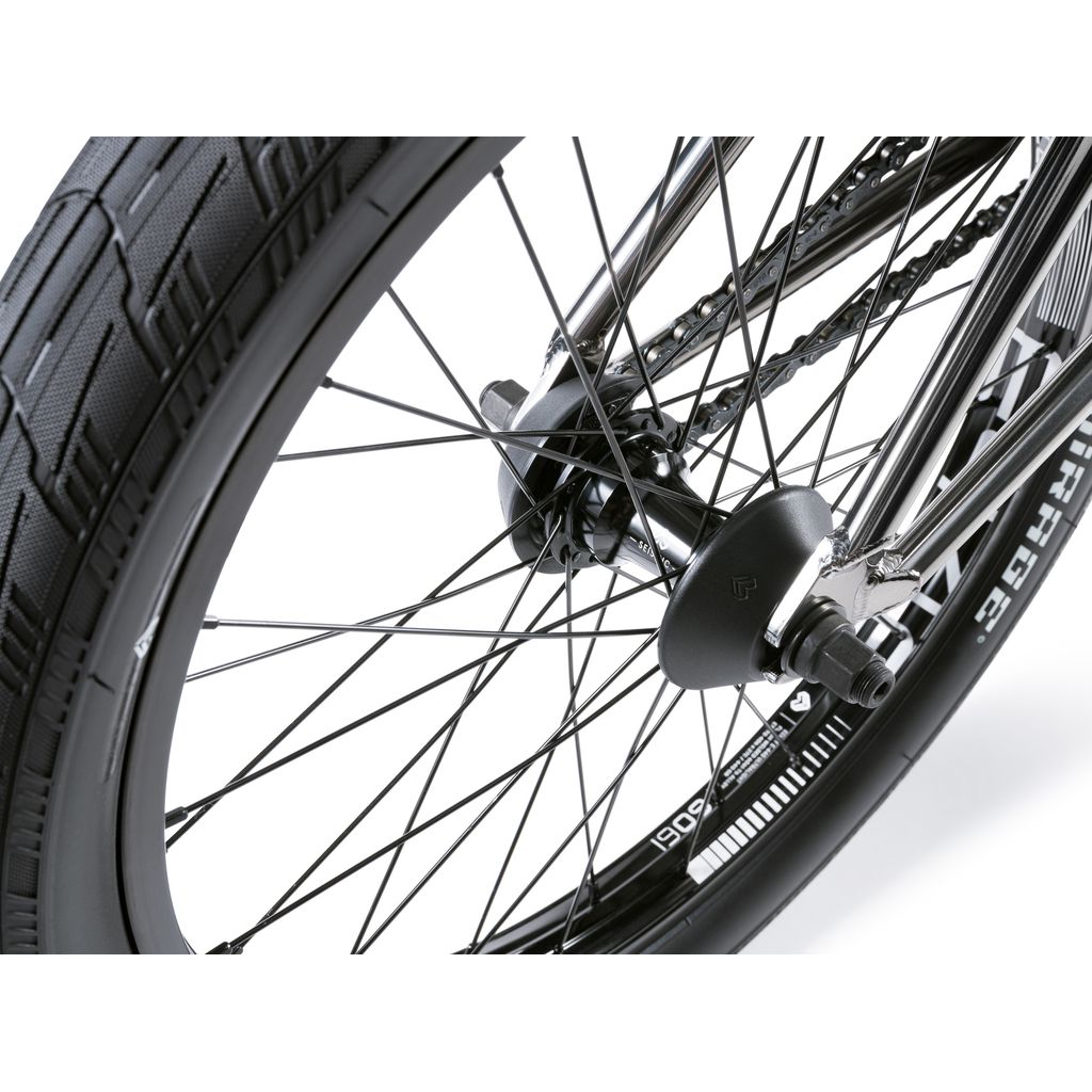 Close-up of a Wethepeople Envy 20 Inch Bike wheel, showing the black tire, intricate spokes, and central hub, exuding BMX precision. Part of the bike's frame is visible in the background.