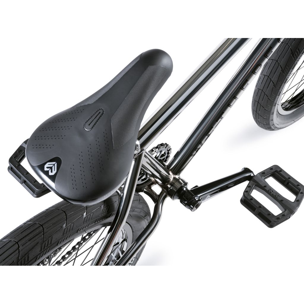 Close-up of the Wethepeople Envy 20 Inch Bike, displaying its black perforated seat, silver frame, and textured black tires—a true masterpiece of craftsmanship.