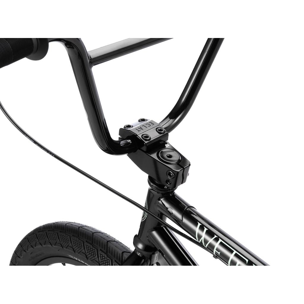 Close-up view of the Wethepeople Havoc 20 Inch Bike's black handlebars, front wheel, and stem, featuring Eclat parts, visible cable routing, and part of the chromo frame.