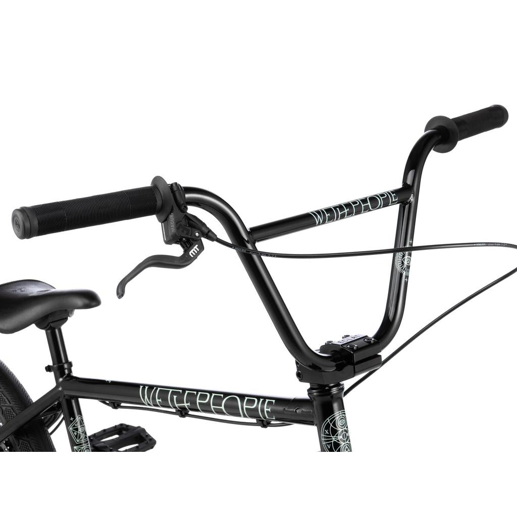 Close-up of the Wethepeople Havoc 20 Inch Bike’s black BMX handlebar with grips, brake lever, and cables. The Chromo frame and handlebar proudly display the Wethepeople brand name.
