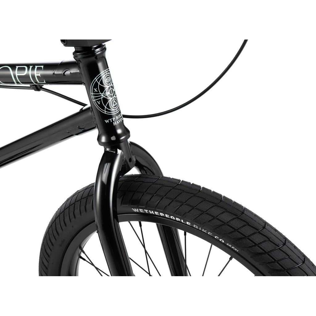 Close-up of the Wethepeople Havoc 22 Inch Bike, showing its black frame with white geometric design, front wheel and fork, disc brake-ready features, and visible branding on both the tire and frame.