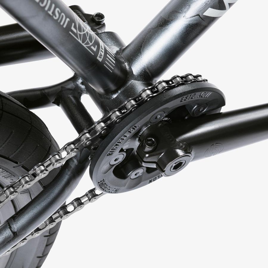 Close-up view of a bicycle's crankset, chainring, and chain on the sleek black frame of a Wethepeople Justice 20 Inch Bike.