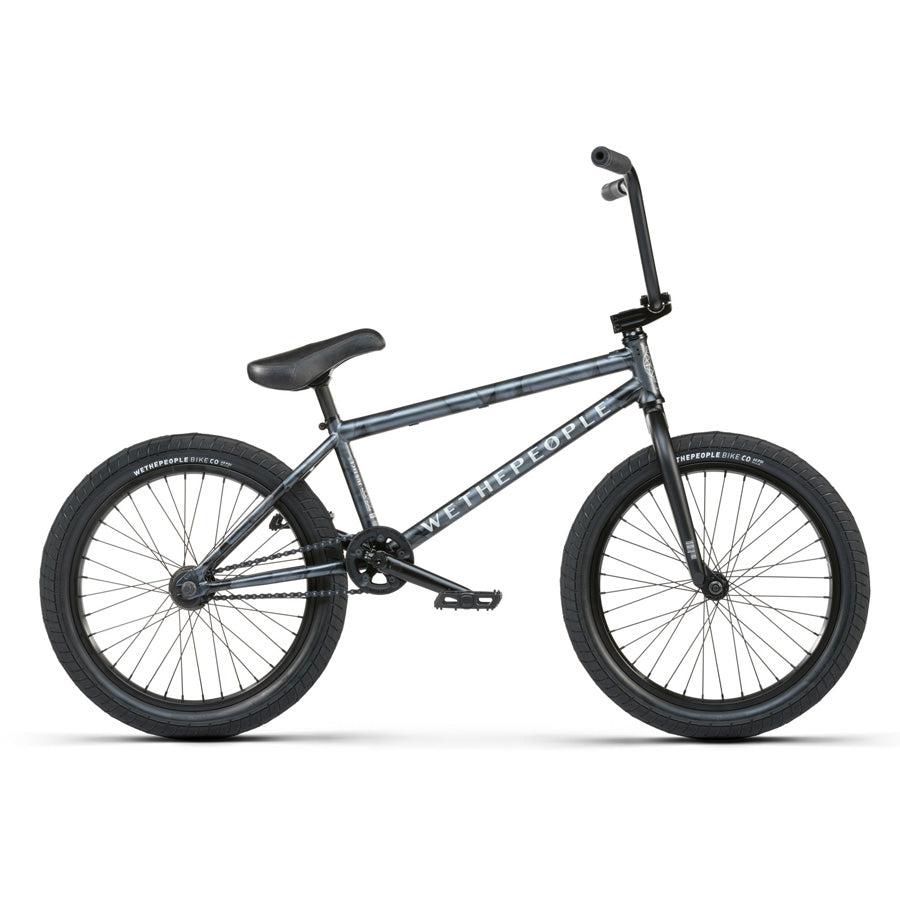 The Wethepeople Justice 20 Inch Bike features a black and gray frame, knobby tires, and a single gear. The brand "Wethepeople" is prominently displayed on the frame, exemplifying its high-quality BMX components.
