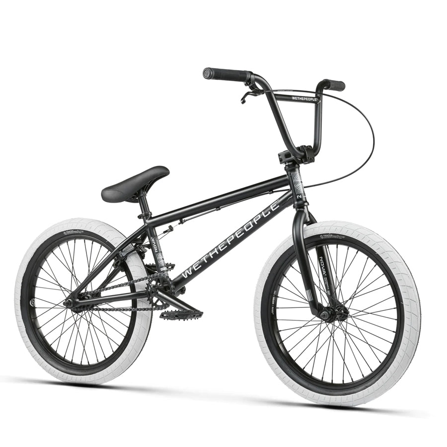 The Wethepeople Nova 20 Inch Bike features a black frame with "WETHEPEOPLE" branding, white tires, and a raised handlebar. It is equipped with Salt Rookie Cranks for optimal performance and style.