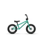 A Wethepeople Prime 12 Inch Balance Bike in small teal with black handlebars, seat, and tires is shown in profile on a white background.