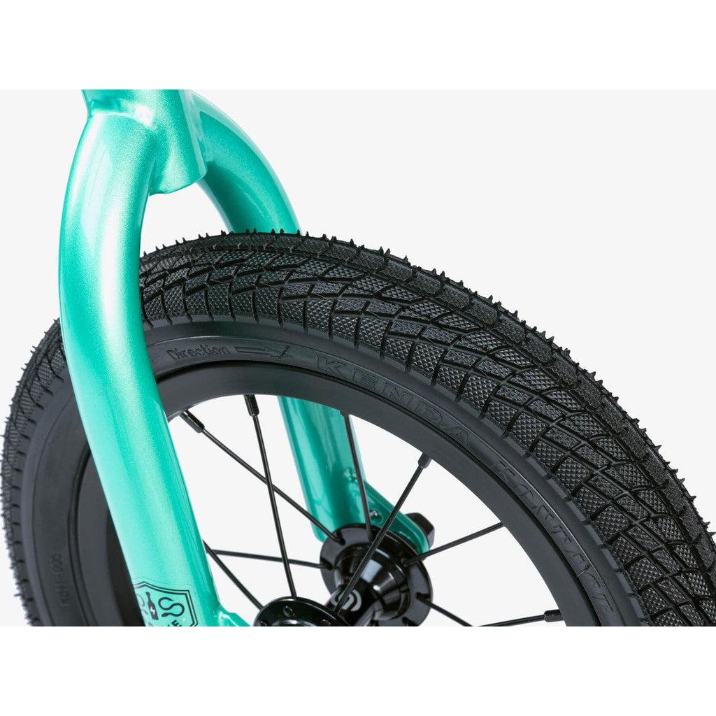 Close-up view of a black bicycle tire with textured tread, attached to a teal-colored fork on a Wethepeople Prime 12 Inch Balance Bike.