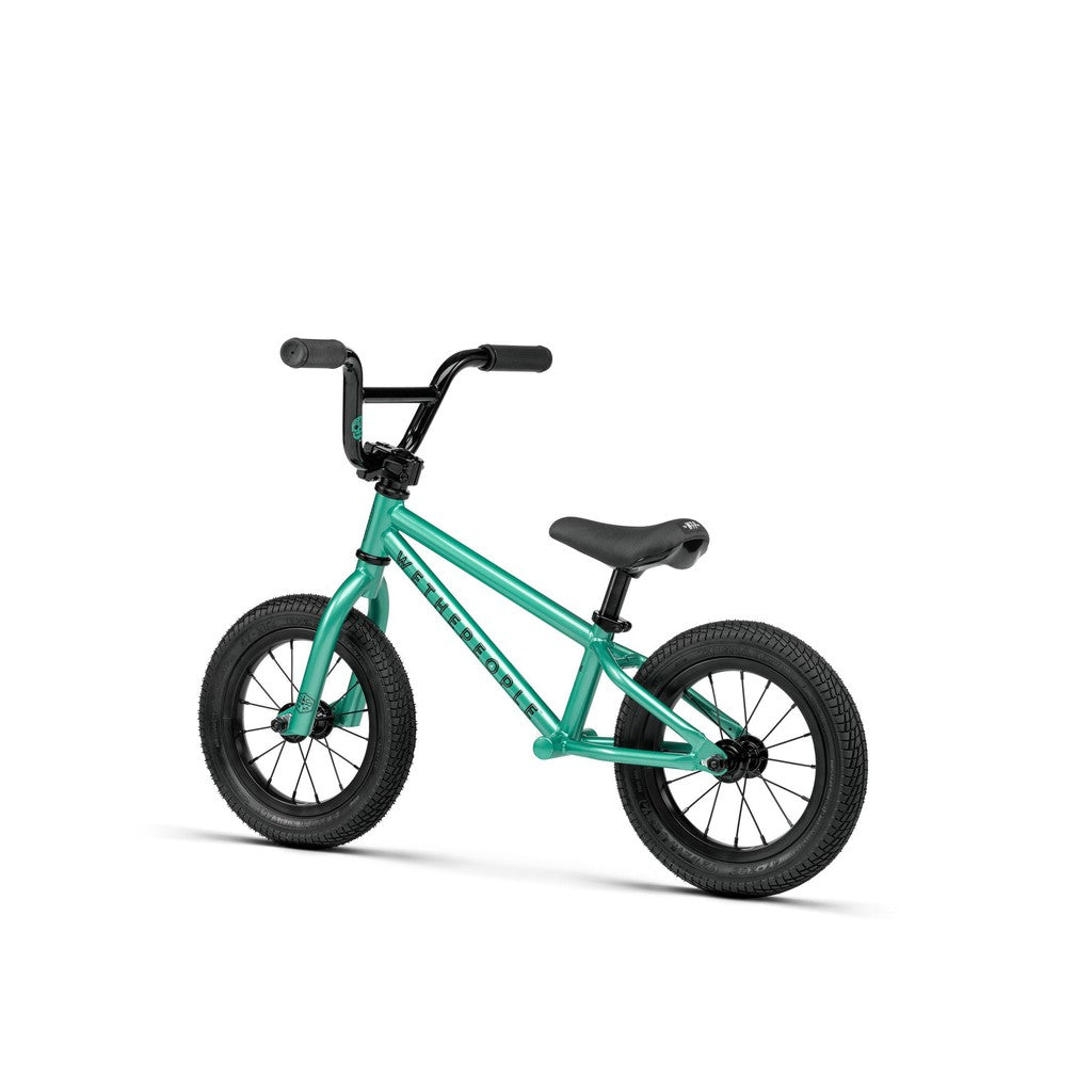 A turquoise Wethepeople Prime 12 Inch Balance Bike for children, with black BMX-style handlebars, seat, and tires, shown against a white background.