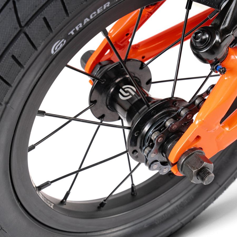A close up of the front wheel of a Wethepeople Prime Drive 12 Inch Bike.