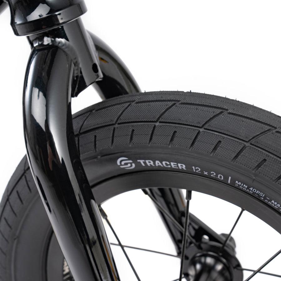 A close up view of a black Wethepeople Prime Drive 12 Inch Bike tire.