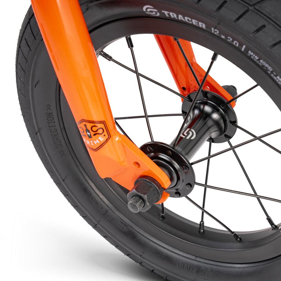 A close up image of an orange Wethepeople Prime Drive 12 Inch Bike tire.