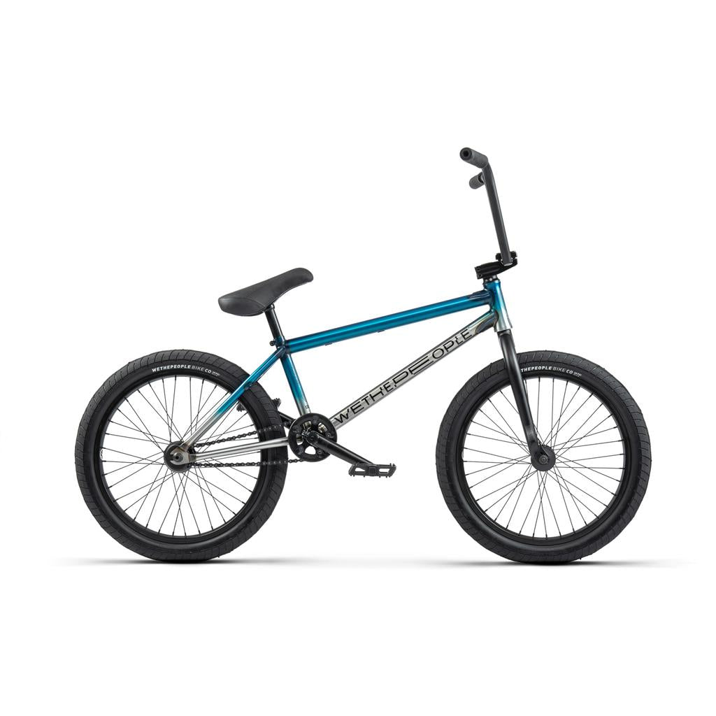 The Wethepeople Reason Shift 20 Inch Bike showcases a striking blue and black design with thick black tires, a cushioned seat, and durable handlebars. Its sturdy chromoly frame features a crossbar and rear wheel pegs for added thrill.