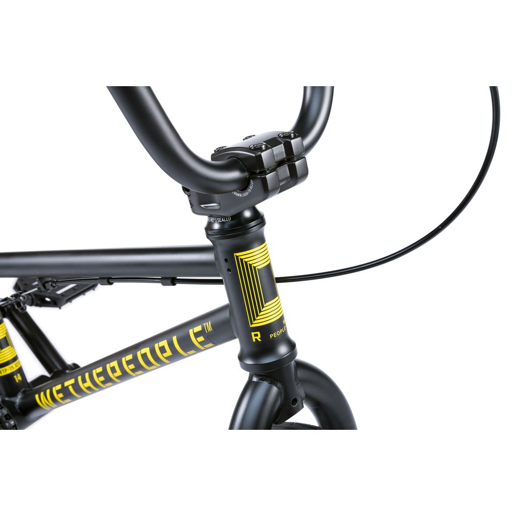 Close-up of the front section of the Wethepeople Riot 14 Inch Bike, a black BMX with yellow geometric graphics, "WETHEPEOPLE" branding on the frame, and strong Chromoly cranks for extra durability.