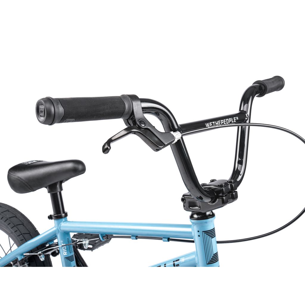 Close-up of the Wethepeople Riot 14 Inch Bike BMX in blue, featuring handlebars, brake lever, seat, frame with "Wethepeople" branding on the handlebars, and chromoly cranks.