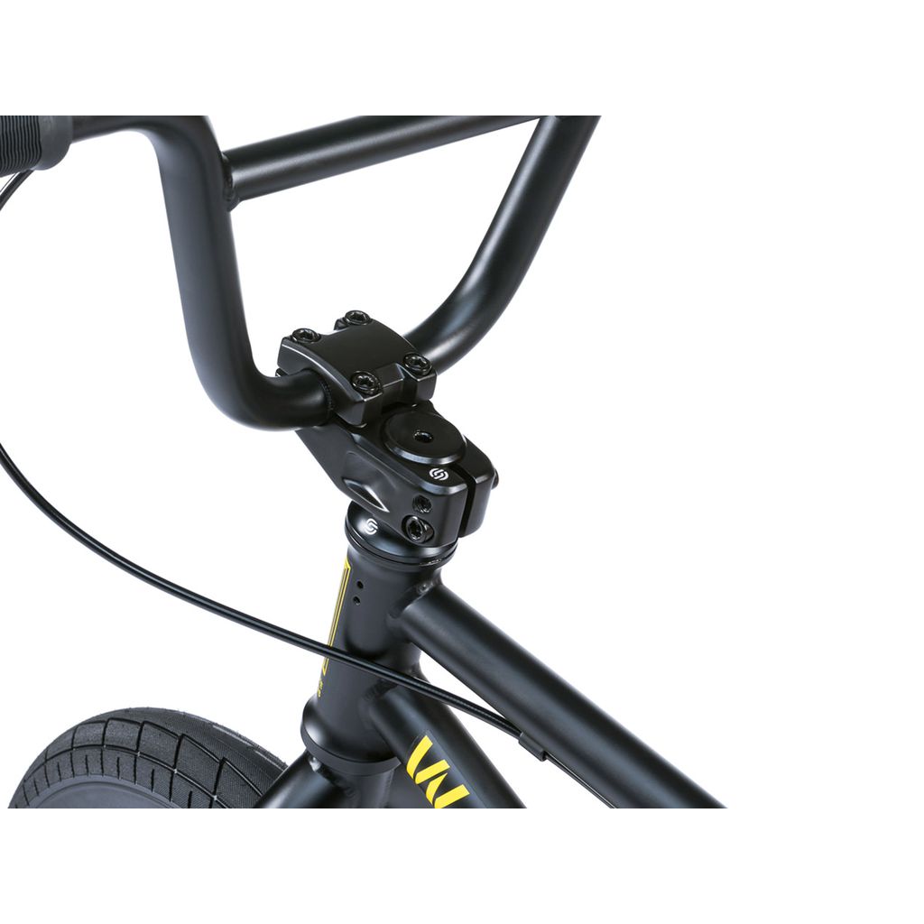 Close-up view of the Wethepeople Riot 14 Inch Bike's black handlebars, stem, and front wheel, highlighting cable routing and a section of the tire.