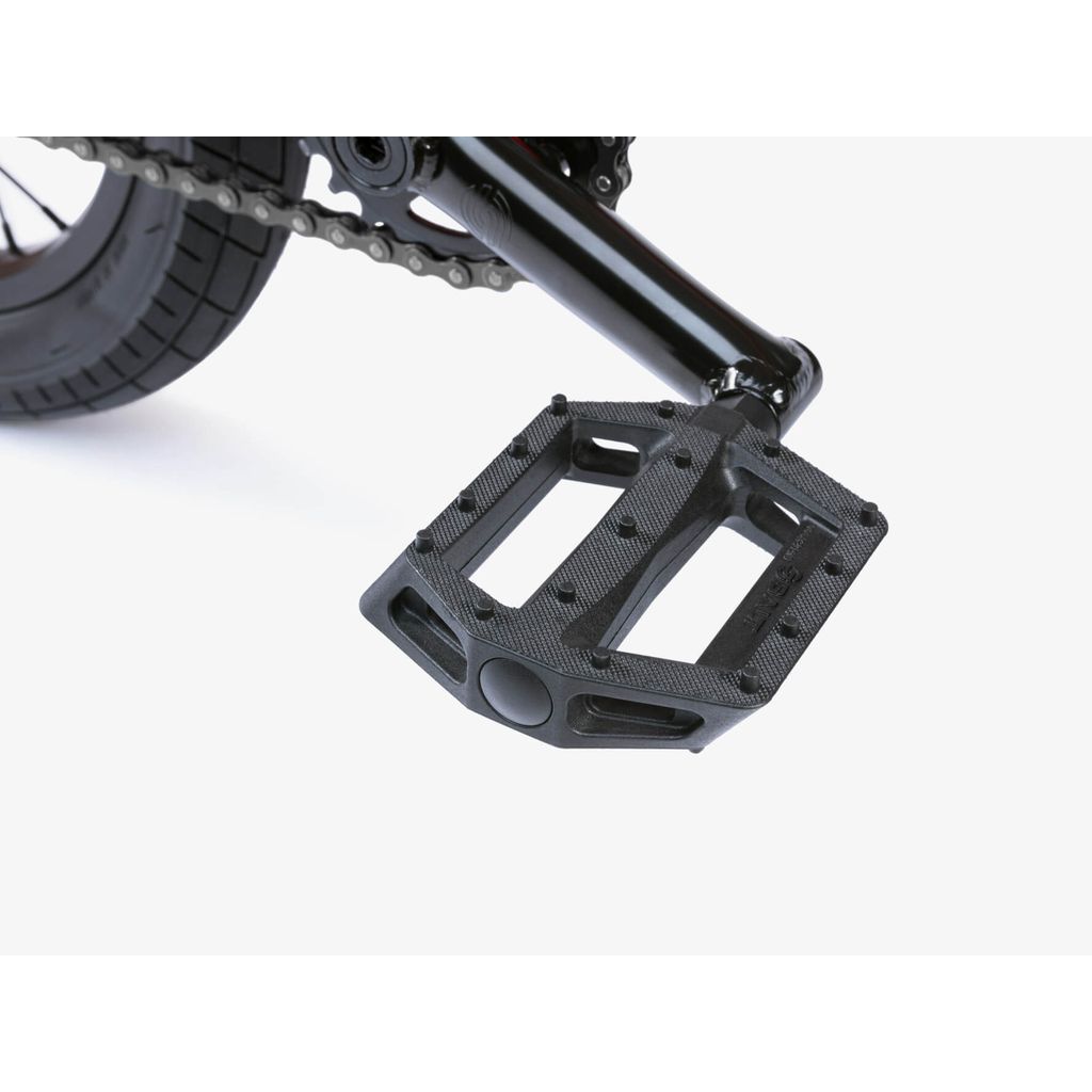 Close-up of a black pedal on sturdy Chromoly Cranks, with chain and rear wheel visible—ideal for the Wethepeople Riot 14 Inch Bike or any BMX ride.