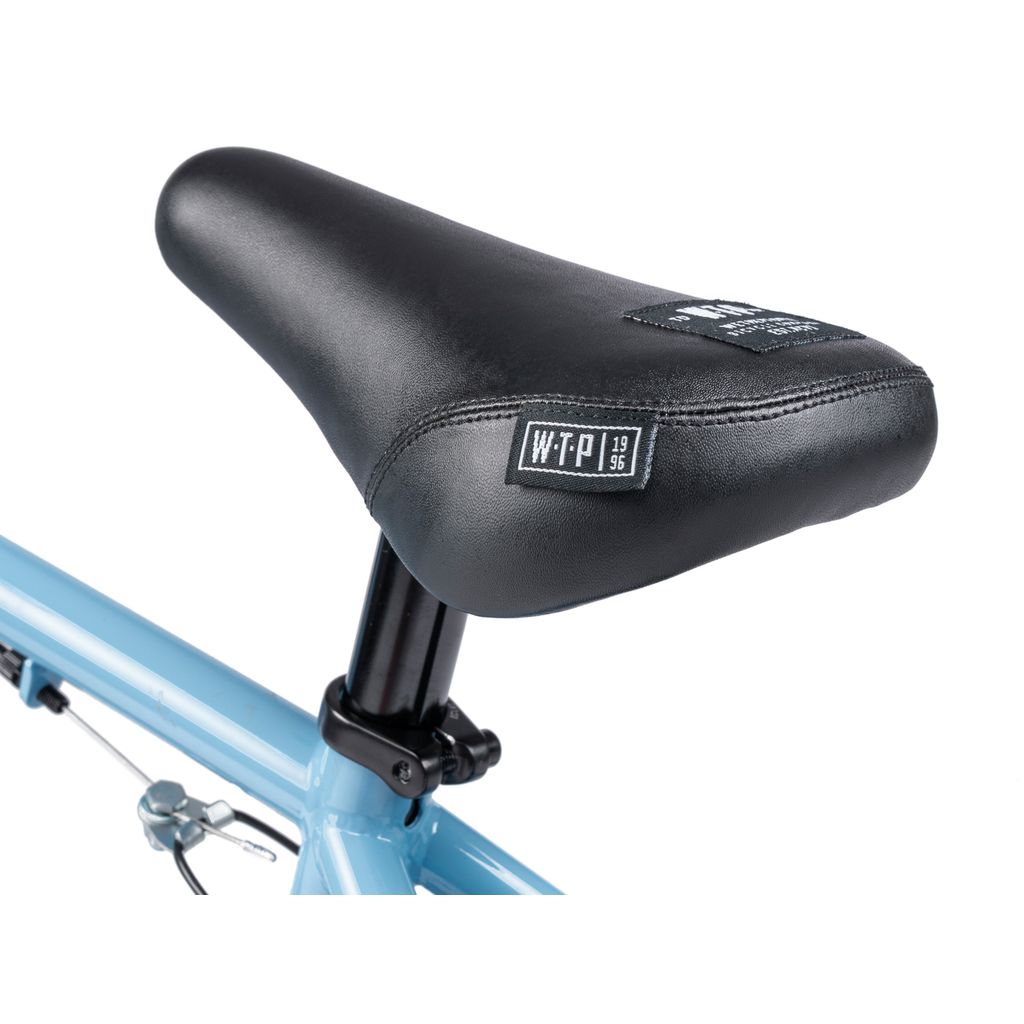 Close-up of the black seat with a "WTP" logo, mounted on the light blue frame of the Wethepeople Riot 14 Inch Bike.