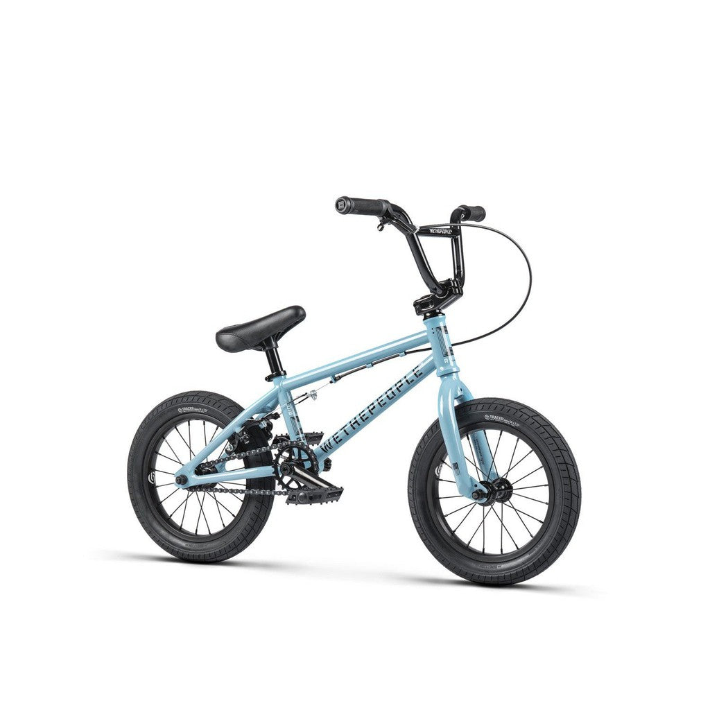 The Wethepeople Riot 14 Inch Bike, a light blue BMX for kids, features black tires, pedals, seat, handlebars, and tough Chromoly cranks—all displayed on a plain white background.
