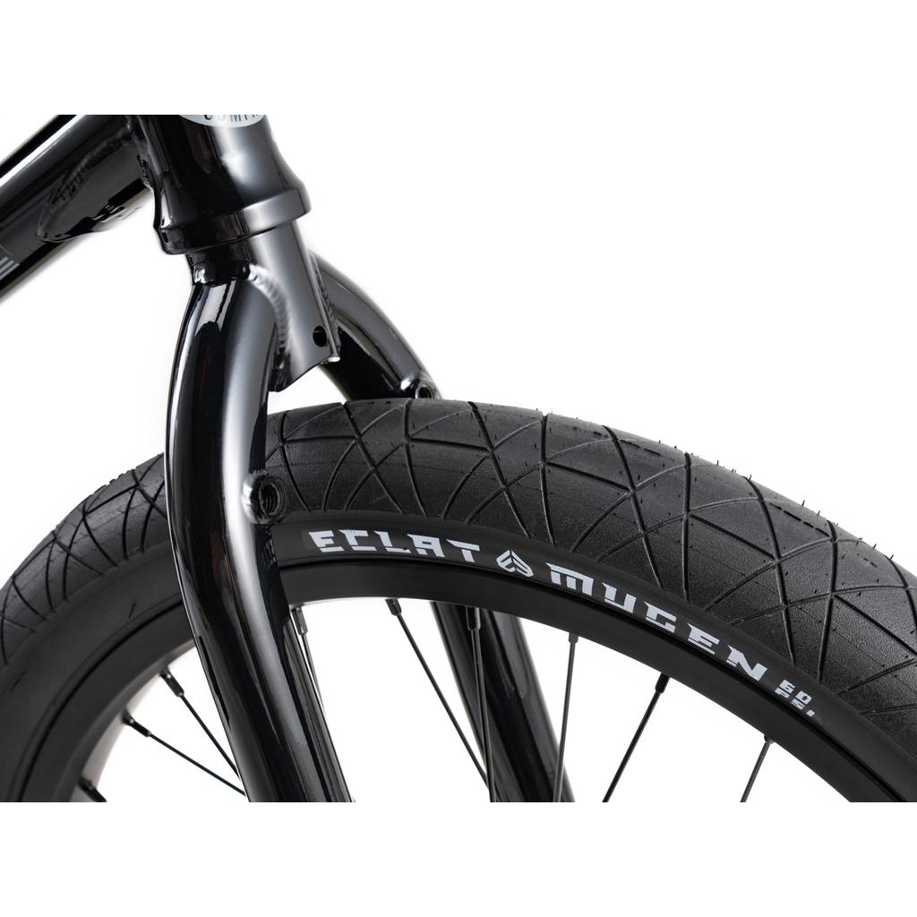 Close-up of a black fork and tire on the Wethepeople Sinus Flatland 20 Inch Bike, with the "Eclat Mugen" logo visible on the flatland-specific tire sidewall against a white background.