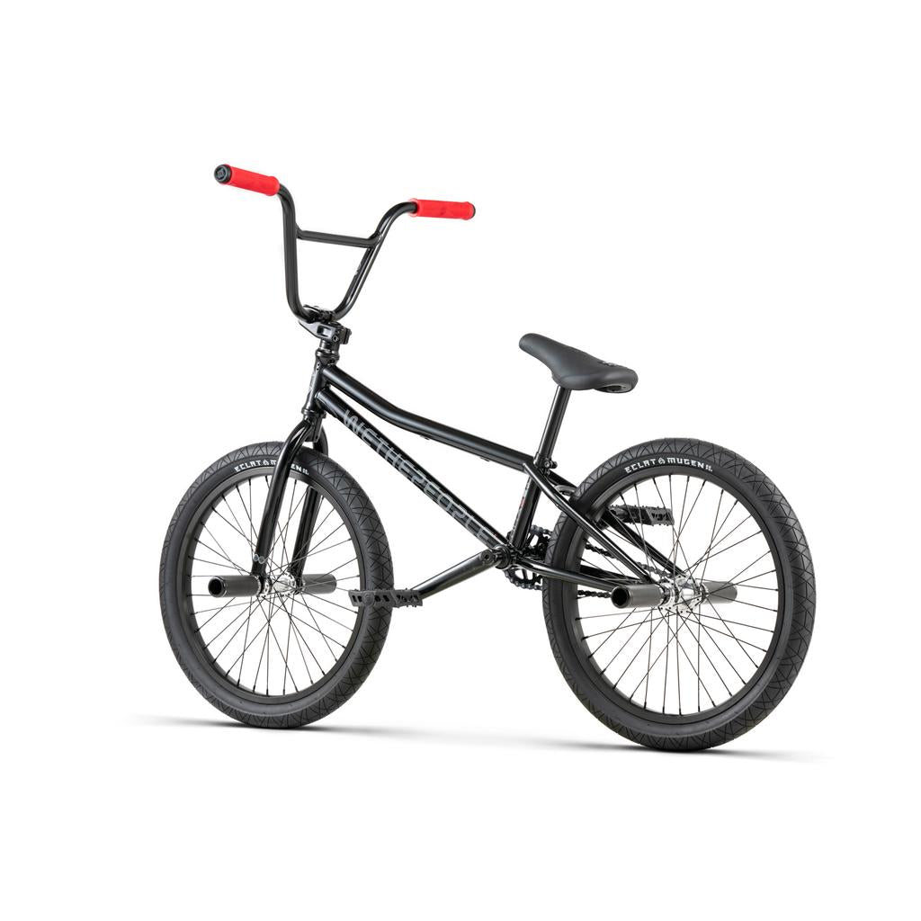 The Wethepeople Sinus Flatland 20 Inch Bike features a black frame, red handlebar grips, thick Mugen flatland tires, a padded seat, and a hybrid freecoaster hub, displayed on a plain white background.