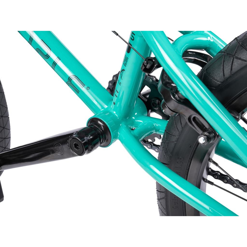 Close-up of a turquoise Wethepeople Sinus Flatland 20 Inch Bike frame highlighting the bottom bracket, crank arm, and rear wheel tire.