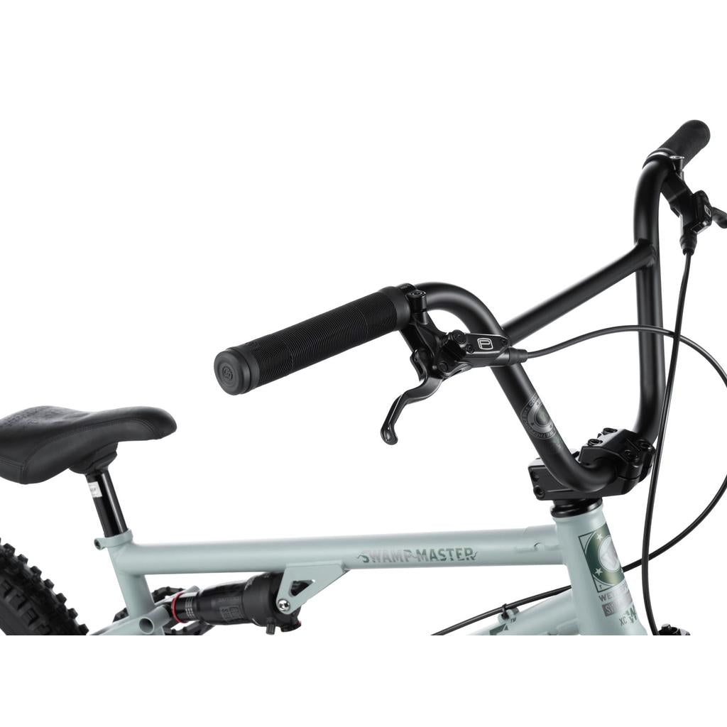 Close-up view of the Wethepeople Swampmaster 20 Inch Bike’s handlebar, brake lever, seat, and part of the frame against a white background, showcasing its essential BMX components.