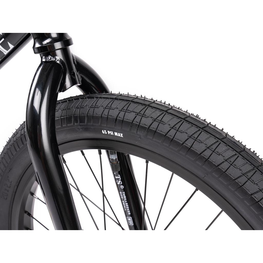 Close-up of the Wethepeople Thrillseeker 20 Inch Bike's black front tire and fork, showing tread details and "65 PSI MAX," with Salt Thrillseeker handlebars above the Hi-Ten frame.