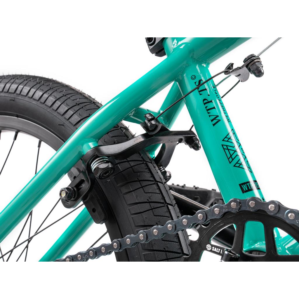 Close-up of the Wethepeople Thrillseeker 20 Inch Bike in teal, highlighting its Hi-Ten frame, rear brake mechanism, tire, chain, and part of the crankset.