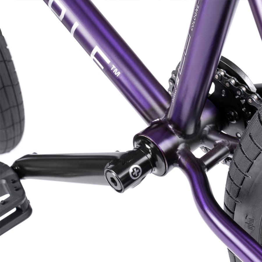 Close-up of a Wethepeople Trust 20 Inch Cassette/Hybrid Bike frame in purple, highlighting the crankset, pedal, rear tire, and Eclat Shift Freecoaster Hub.