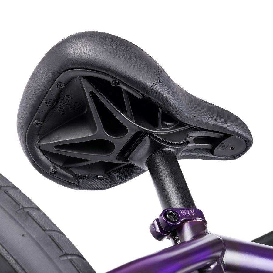 Close-up view of a black bicycle seat attached to a seat post, showing the underside structure and rear wheel on a Wethepeople Trust 20 Inch Cassette/Hybrid Bike.
